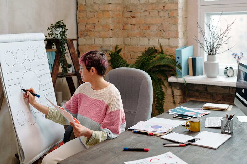 A woman in a knitted sweater draws on a flipchart in a stylish brick office setting.
